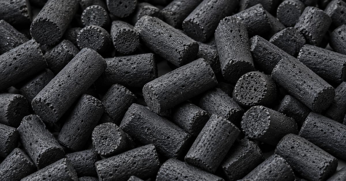 Close-up of extruded cylindrical activated carbon pellets showing the porous cut ends and uniform diameter
